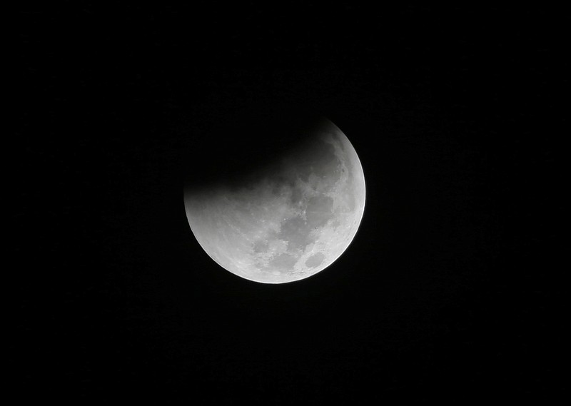 FILE - In this Saturday Aug. 28, 2018 file photo, Earth starts to cast its shadow on the moon during a complete lunar eclipse seen from Jakarta, Indonesia. Starting Sunday evening, Jan. 20, 2019, all of North and South America will be able to see the only total lunar eclipse of 2019 from start to finish this weekend. (AP Photo/Tatan Syuflana)