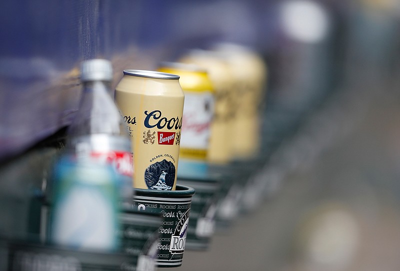 In this June 3, 2018, file photo empty cans of Coors beer sit in beverage holders on the backs of box seats after the ninth inning of a baseball game in Denver. The makers of Budweiser, Coors and other large-scale brewers are placing their bets on cannabis as a way to fight saturated markets and shifting consumer trends.  (AP Photo/David Zalubowski, File)