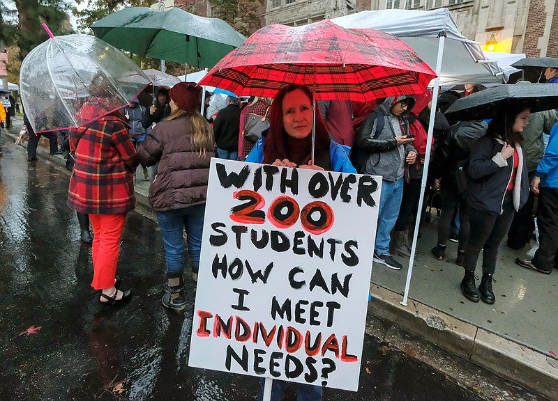 In this Jan. 14, 2019 file photo, teachers strike in the rain outside John Marshall High School in Los Angeles. Teachers who declared a victory after a six-day strike have added momentum to a wave of activism by educators. They've tapped a common theme and found success by framing their cause as a push to improve public education, not just get pay raises.  (AP Photo/Ringo H.W. Chiu, File)