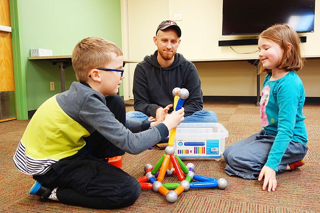 Ben, 8, and Hannah, 6, Snider assemble a creation from magnetic building pieces, while father Shawn Snider looks on. 