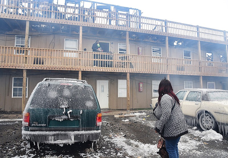 In this Jan. 21, 2019 file photo, the smoke rises from debris as a displaced tenant observes the scene following a fire that destroyed the Evergreen apartments in Holts Summit. 