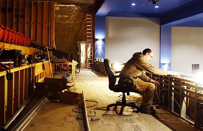 Clayton McOwen, an electrician, works in the balcony of the Brick District Playhouse. 