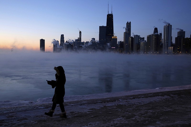 A person walks along the lakeshore, Wednesday, Jan. 30, 2019, in Chicago. A deadly arctic deep freeze enveloped the Midwest with record-breaking temperatures on Wednesday, triggering widespread closures of schools and businesses, and prompting the U.S. Postal Service to take the rare step of suspending mail delivery to a wide swath of the region. (AP Photo/Kiichiro Sato)