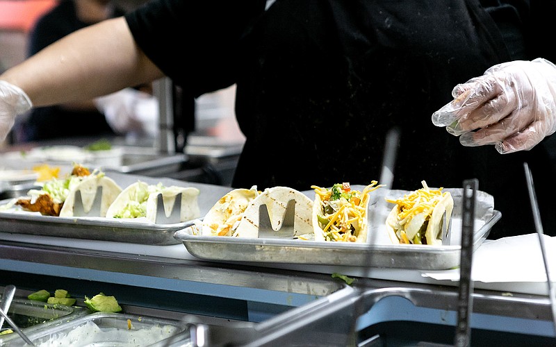 Tacos 4 Life kitchen staff members build tacos Friday, Feb. 1, 2019, on the food line in the restaurant in Texarkana, Texas. Tacos 4 Life donates one meal for every meal bought to a children's charity the company supports.