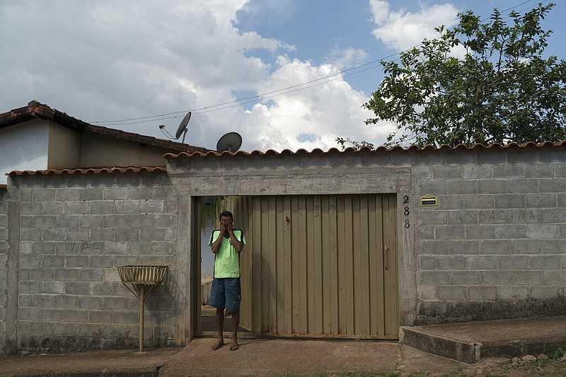Fernando Nunes wipes tears from his face at the doorway of his home, where the wall carries the Portuguese message: "Vale assassin" in Brumadinho, Brazil, Wednesday, Jan. 30, 2019. "I will find my brother," said Fernando, calling the Vale mining company "murderers." His brother had been working in equipment distribution at the mine complex when it collapsed on Jan. 25.