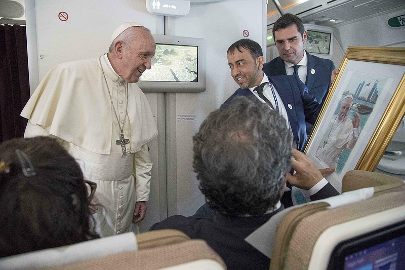 Pope Francis receives a gift from a journalist during his flight from Abu Dhabi to Rome, Tuesday, Feb. 5, 2019. Pope Francis has concluded his historic visit to the Arabian Peninsula with the first-ever papal Mass in the birthplace of Islam. (Luca Zennaro/Pool Photo via AP)