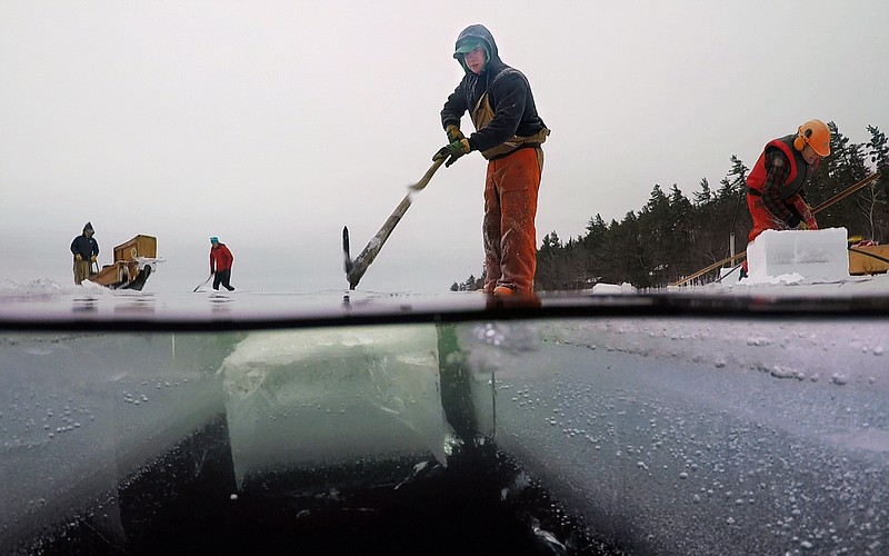 In this Friday, Jan. 18, 2019, photo, Neil Cederberg uses a pick pole to guide a 16 x 19-inch ice block into a channel on Squam Lake at the Rockywold-Deephaven Camps in Holderness, N.H. A 120-year-old tradition continues in order to provide refrigeration for the summer camp's ice boxes. (AP Photo/Robert F. Bukaty)