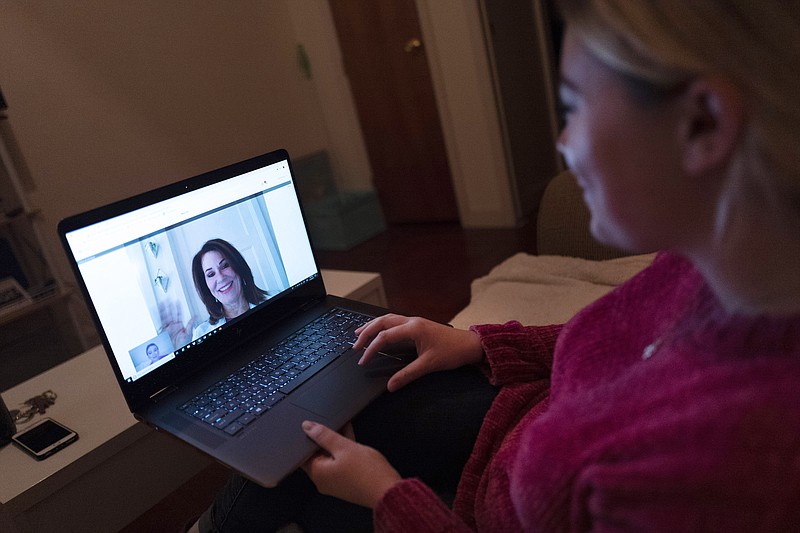 In this Jan. 14, 2019 photo, Caitlin Powers sits in the living room of her Brooklyn apartment in New York, and has a telemedicine video conference with physician, Dr. Deborah Mulligan. (AP Photo/Mark Lennihan)