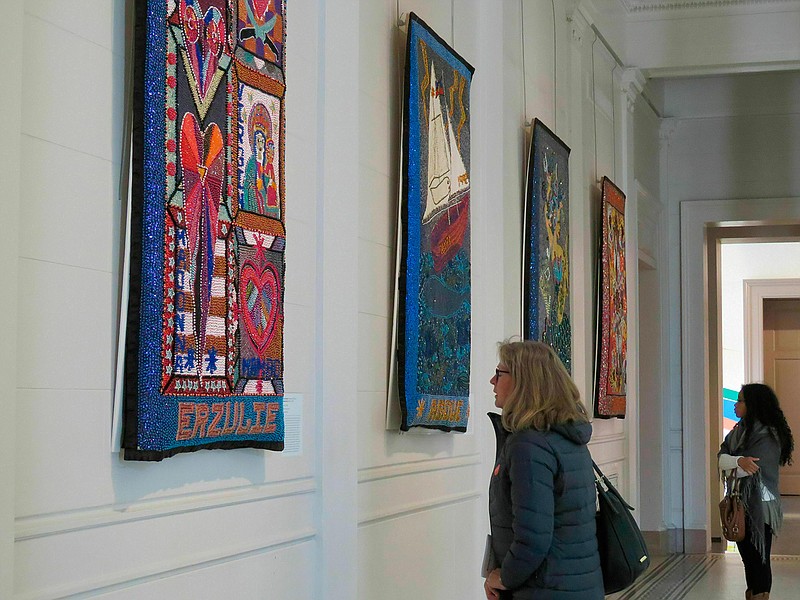 Margot Wittig of Starnberg, Germany, foreground, and Amanda Fleury of Gretna, La., look at giant-sized sequined Vodou flags at the New Orleans Museum of Art on Wednesday, Jan. 30, 2018. The exhibit of work by Louisiana artist Tina Giruard and many Haitian bead artists at a studio in Haiti is titled "Bondye: Between and Beyond" and runs through June 16, 2019. (AP Photo/Janet McConnaughey)