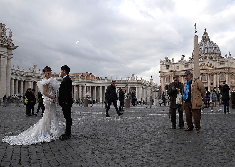 People look at Chinese couple in wedding clothes posing for photos in front of St. Peter's Square at the Vatican, Thursday, Jan. 17, 2019. (AP Photo/Alessandra Tarantino)