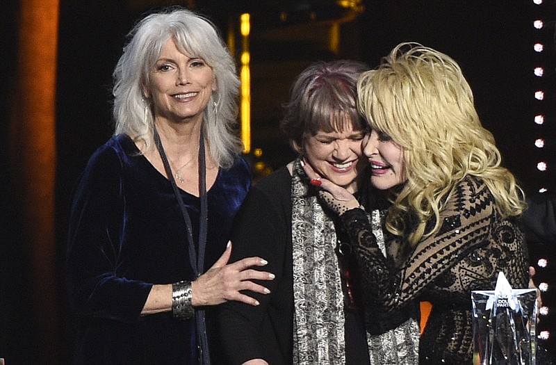 Emmylou Harris, from left, and Linda Ronstadt present Dolly Parton with the MusiCares Person of the Year award on Friday, Feb. 8, 2018, at the Los Angeles Convention Center. (Photo by Chris Pizzello/Invision/AP)