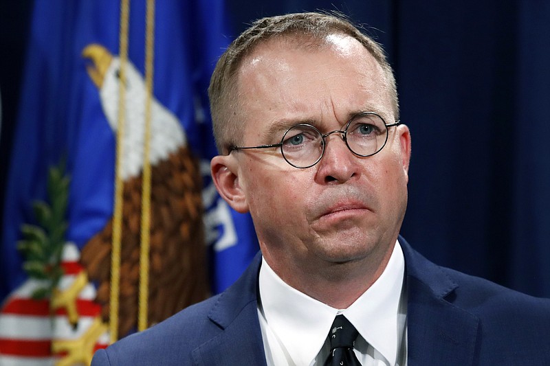 FILE- In this July 11, 2018, file photo Mick Mulvaney, acting director of the Consumer Financial Protection Bureau (CFPB), and Director of the Office of Management, listens during a news conference at the Department of Justice in Washington. White House Acting Chief of Staff Mick Mulvaney isn’t setting any lofty goals for this weekend’s meeting with a bipartisan mix of legislators at Camp David, but he is trying to build relationships across the aisle. (AP Photo/Jacquelyn Martin, File)