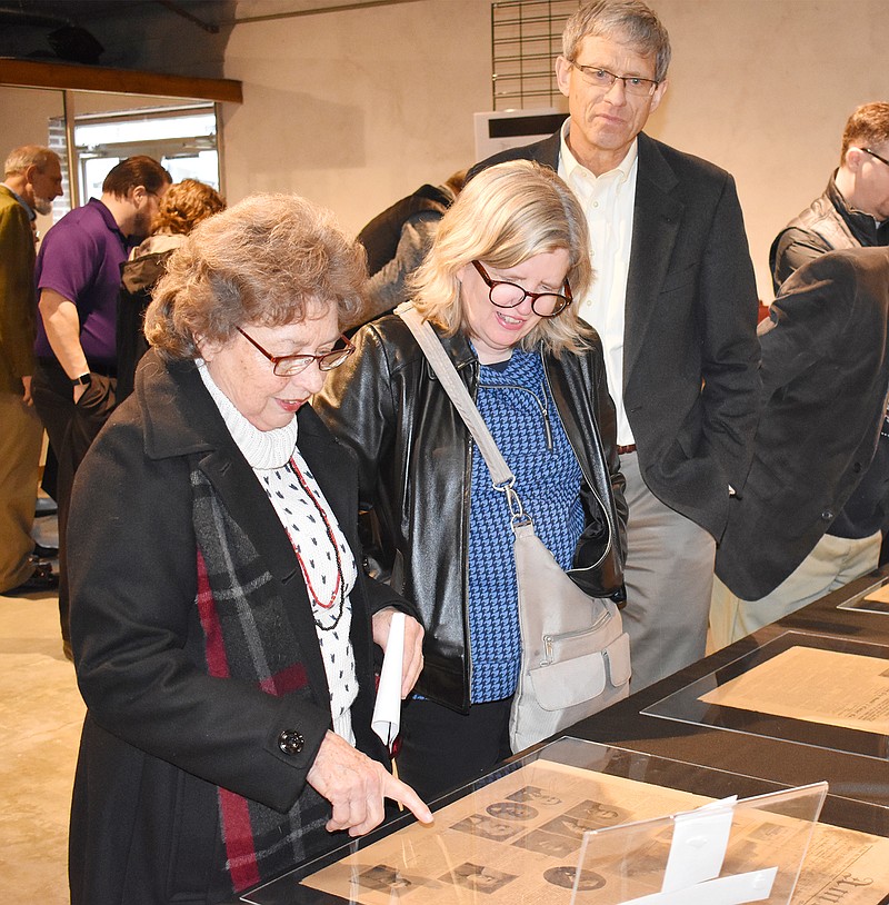 From left, Sharon Gonder and Nina and Mark Kiekhaefer view one of six newspapers Sunday that were inside the 1904 time capsule that was recovered from the capstone of the old St. Mary's Hospital. 