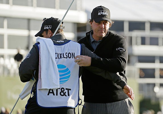 Phil Mickelson is embraced Monday by his caddie and brother, Tim Mickelson, on the 18th green of the Pebble Beach Golf Links after winning the Pebble Beach Pro-Am in Pebble Beach, Calif.