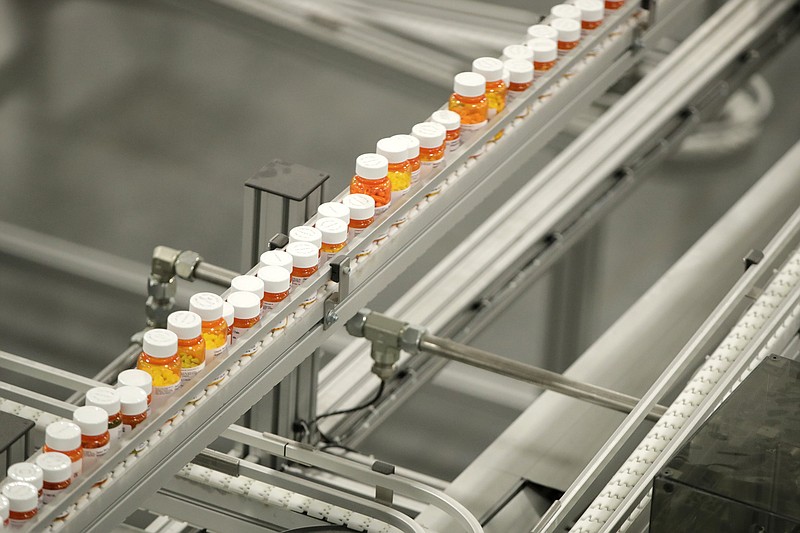 FILE- In this July 10, 2018, file photo bottles of medicine ride on a belt at the Express Scripts mail-in pharmacy warehouse in Florence, N.J. As Democrats in Congress consider whether to back a revamped regional trade pact being pushed by President Donald Trump, they’re zeroing in on a new point of conflict: Drug prices. They contend that the new pact would force Americans to pay more for prescription drugs, and their argument has dimmed the outlook for one of Trump’s signature causes. (AP Photo/Julio Cortez, File)