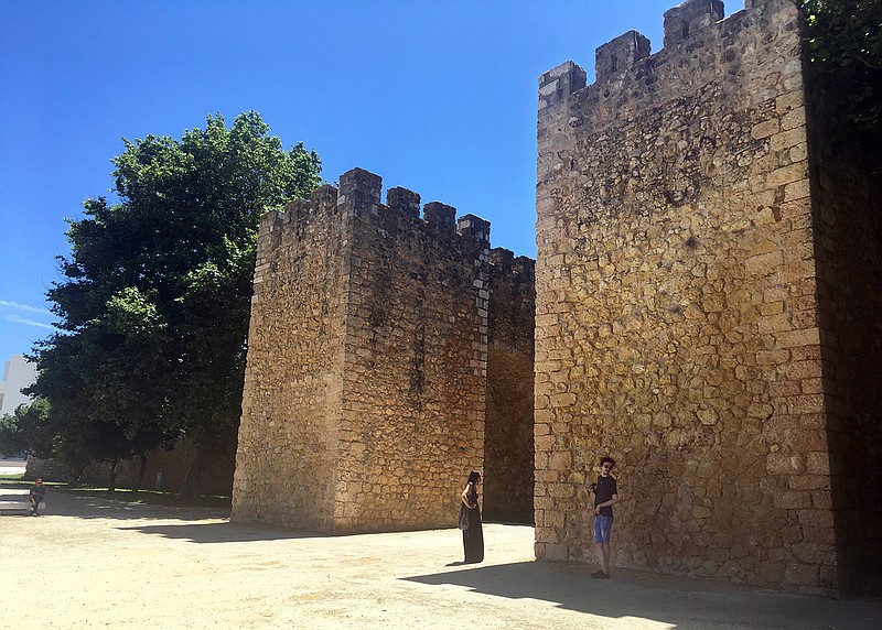 In this June 27, 2018, photo, tourists stand in front of the medieval-era Castle of Lagos in Lagos, Portugal. Lagos, a striking Portuguese beach town of charming coastlines and slightly sandstone cliffs, is the birthplace of the African slave trade in Europe. (AP Photo/Russell Contreras)