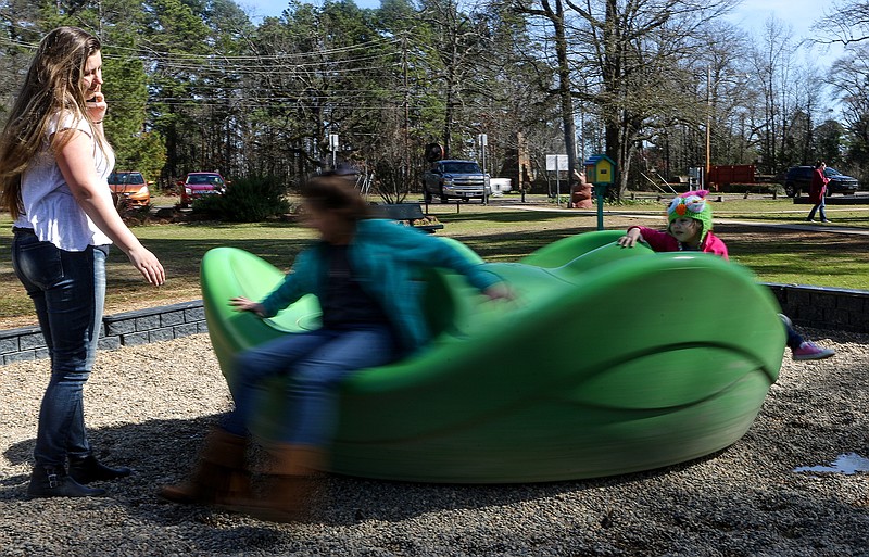 Autumn Foster spins Abigail Tidwell and Maisie Elmer on one of the playground merry-go-rounds Wednesday at Spring Lake Park in Texarkana, Texas.