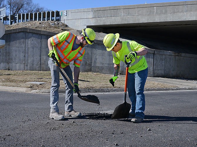 MoDOT crew members Blake Lamberson, left, and Ryan Koening fill a pot hole Thursday, Feb. 14, 2019, on the U.S. 50 exit to downtown Jefferson City.