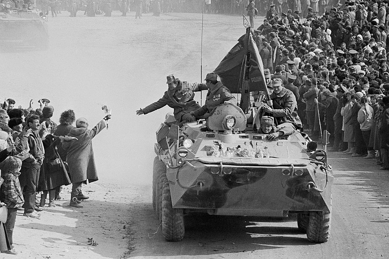 In this photo taken on Feb. 15, 1989, people and relatives greet Soviet Army soldiers driving on their armored personnel carriers after crossing a bridge on the border between Afghanistan and then Soviet Uzbekistan near the Uzbek town of Termez, Uzbekistan. When the Soviet Union completed its troops withdrawal from Afghanistan on this day, it was widely hailed as a much-anticipated end to a bloody quagmire, but public perceptions have changed and many Russians now see the 10-year Soviet war in Afghanistan as a necessary and largely successful endeavor. (AP Photo/Alexander Zemlianichenko)