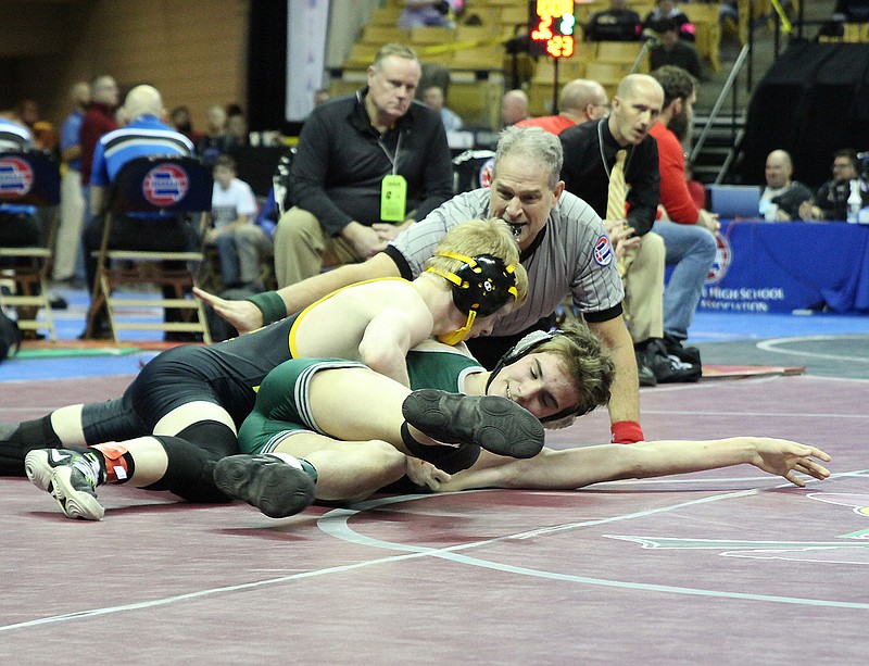 Fulton sophomore Sam Hrabovsky tries to work St. Joseph Lafayette freshman Austin Allen onto his back during their Class 2 first-round match at 120 pounds Thursday morning in the 89th MSHSAA Wrestling Championships at Mizzou Arena in Columbia. Hrabovsky (32-0) — who is seeking a second straight undefeated state title — pinned Allen in 1:09. Fulton head coach Ryan Morts (right) and assistant coach Tim Echelmeier watch in the background.