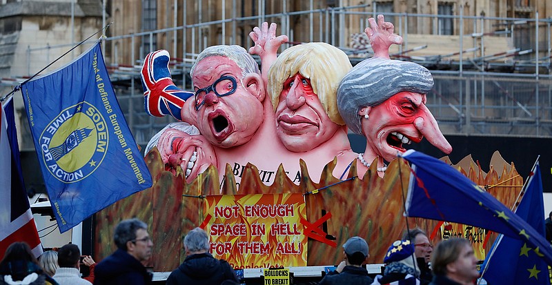 Anti-Brexit demonstrators stand Thursday, Feb. 14, 2019, next to a van with large cartoon style portraits of leading British politicians including, from left, David Davis, Michael Gove, Boris Johnson and Prime Minister Theresa May, outside the Palace of Westminster in London.