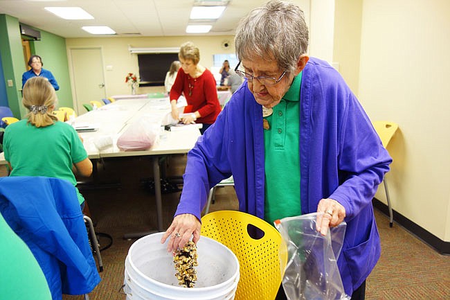 Helen West rolls a shortening-covered pine cone in birdseed. These fat-packed, easy-to-make bird feeders are a great way to provide an energy boost for your feathered friends during the cold winter months.