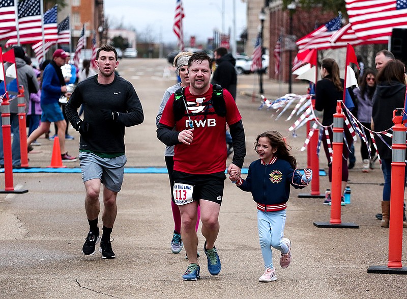  Canely Newberry joins her father, Joseph, as he runs toward the finish line Sunday at the 12th annual Run the Line Half-Marathon in Texarkana.