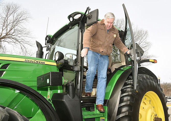 In this Feb. 19, 2019, photo, Missouri Gov. Mike Parson climbs out of the John Deere tractor  he had just driven to the state Capitol from the Governor's Mansion. He met with a group of FFA students gathered from around the state to be at the Capitol and be a part of the agriculture workforce development discussion. 