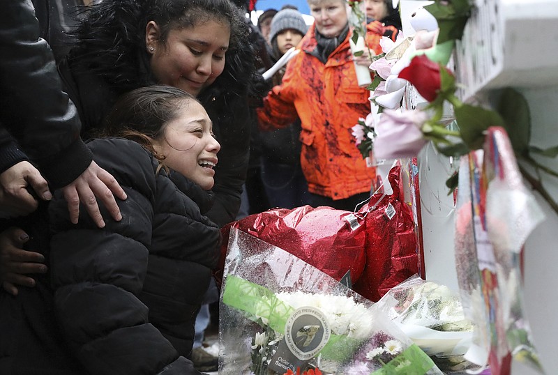 One of victim Vicente Juarez's daughter Diana Juarez cries at a makeshift memorial Sunday, Feb. 17, 2019, in Aurora, Ill., near Henry Pratt Co. manufacturing company where several were killed on Friday. Authorities say an initial background check five years ago failed to flag an out-of-state felony conviction that would have prevented a man from buying the gun he used in the mass shooting in Aurora. (AP Photo/Nam Y. Huh)