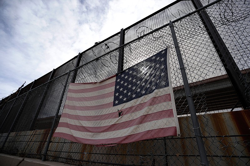 A U.S. flag hangs on a border barrier Jan. 21 in El Paso, Texas. Such barriers have been a part of El Paso for decades and are now being expanded, even as the fight over President Donald Trump's desire to wall off the entire U.S.-Mexico border has sparked the longest government shutdown in the nation's history.