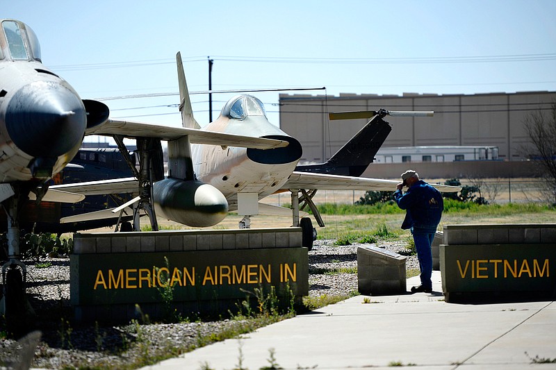 A man reads a plaque Saturday at a memorial commemorating the aircraft of the Vietnam War and the pilots who flew them at the CAF Airpower Museum in Midland, Texas. From the foreground are a F-105 Thunderchief and an F-100 Super Sabre. The tail rotor of a UH-1 Huey helicopter is visible in the background.