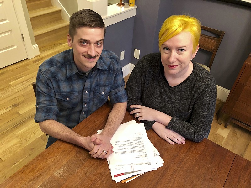 Husband and wife Andy Kraft and Amy Elias, of Portland, Ore., pose with their 2018 tax paperwork in their Portland home on Monday, Feb. 18, 2019. The couple got a small refund last year but this year owe more than $10,000 in taxes under the new tax law. (AP Photo/Gillian Flaccus)