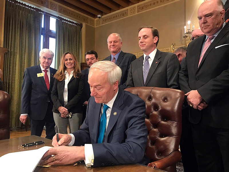 Arkansas Gov. Asa Hutchinson signs into law a $97 million plan to cut the state's top income tax rate during a ceremony at the state Capitol in Little Rock, Ark., on Tuesday, Feb. 19, 2019. (AP Photo/Andrew DeMillo)