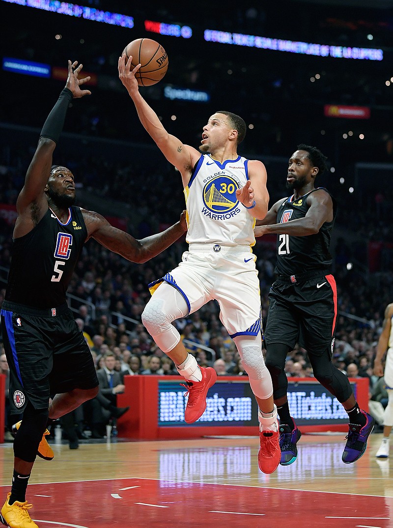In this Jan. 18, 2019, file photo, Golden State Warriors guard Stephen Curry, center, shoots as Los Angeles Clippers forward Montrezl Harrell, left, and guard Patrick Beverley defend during the second half of an NBA basketball game, in Los Angeles. Golden State is still the favorite for a fourth title in five years.c "Every year is a new challenge, different circumstances," Golden State guard Stephen Curry said. "We are motivated. We understand what's at stake." (AP Photo/Mark J. Terrill, File)