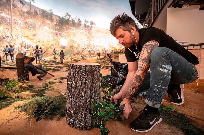 In this Friday, Feb 15, 2019 photo, a worker puts some final touches on the diorama that is part of the Atlanta Cyclorama display at the Atlanta History Center on Friday, Feb 15, 2019, in Atlanta. The Atlanta Cyclorama depicts charging horses, wounded soldiers, cannon blasts and smoke as Union troops defeated Confederate forces and then torched much of the city.(AP Photo/ Ron Harris)