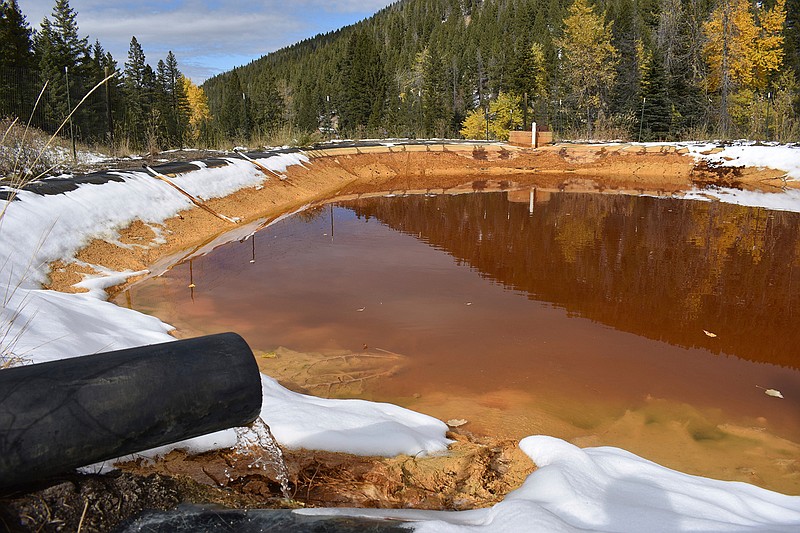 In this Oct. 12, 2018 photo, water contaminated with arsenic, lead and zinc flows from a pipe out of the Lee Mountain mine and into a holding pond near Rimini, Mont. The community is part of the Upper Tenmile Creek Superfund site, where dozens of abandoned mines have left water supplies polluted and residents must use bottled water. (AP Photo/Matthew Brown)