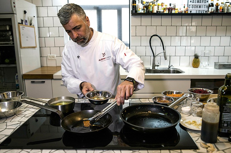 In this Wednesday, Jan. 16, 2019 photo, chef Amir Ilan prepares a lab-grown steak during a presentation by the Israeli company Aleph Farms, in Jaffa, Israel. Several Israeli start-ups have joined a handful of companies around the globe trying to develop lab-grown meat, something they see as a solution to the needs of the world's ever-growing population and burgeoning demand for food. (AP Photo/Tsafrir Abayov)