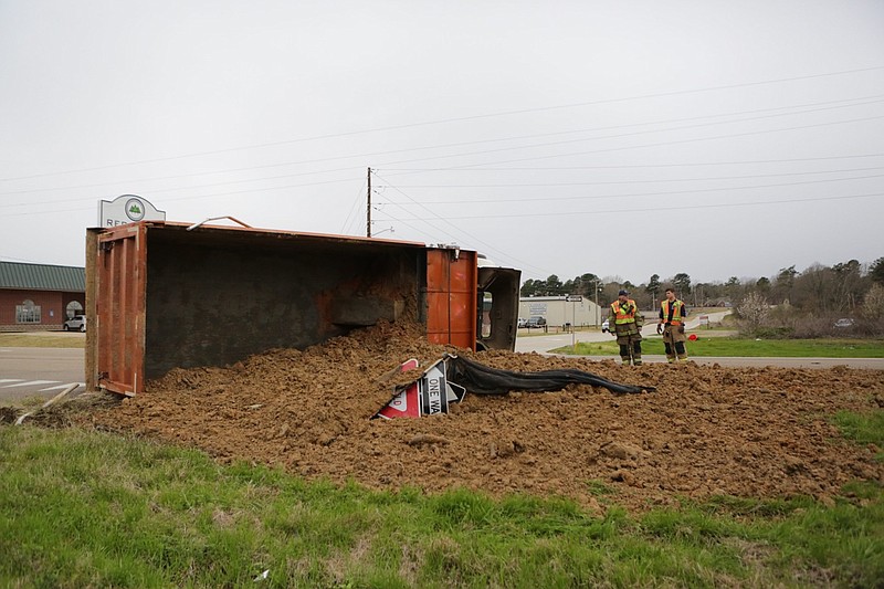 Texarkana, Ark., firefighters stand next to a truck carrying dirt that flipped over on U.S. Highway 71 at the intersection of Forest Lake Drive in Texarkana, Texas on Tuesday morning.

