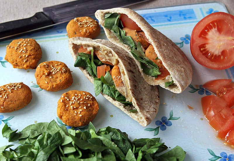 Sweet potato falafels, sprinkled with sesame seeds, are used to make a sandwich in a pita pocket, along with tomatoes, spinach and tahini sauce mixed with garlic and lemon juice. (J.B. Forbes/St. Louis Post-Dispatch/TNS) 