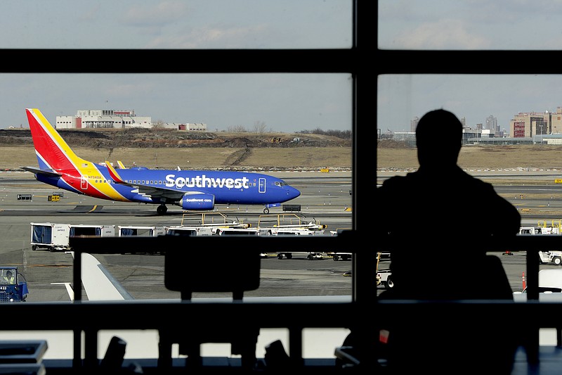 FILE- In this Jan. 25, 2019, file photo a Southwest Airlines jet moves on the runway as a person eats at a terminal restaurant at LaGuardia Airport in New York.  The CEO of Southwest Airlines Gary Kelly said Tuesday, March 5, that a spike in planes ruled out of service for mechanical items is costing the carrier millions each week because of delayed and canceled flights. (AP Photo/Julio Cortez, File)
