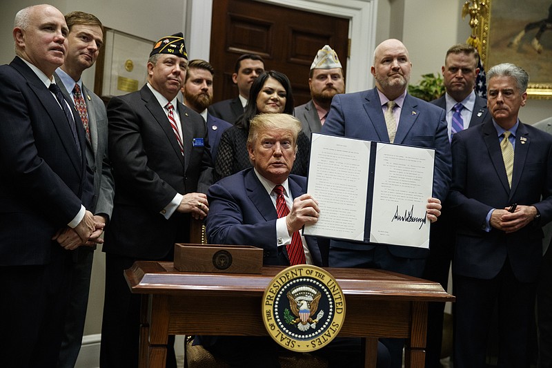 President Donald Trump shows off an executive order on a "National Roadmap to Empower Veterans and End Veteran Suicide," in the Roosevelt Room of the White House, Tuesday, March 5, 2019, in Washington. (AP Photo/ Evan Vucci)