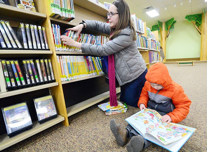 Cooper Kline, 4, and mother, Sarah, look at books to check out Tuesday, March 5, 2019, at the Holts Summit Public Library during its grand opening.