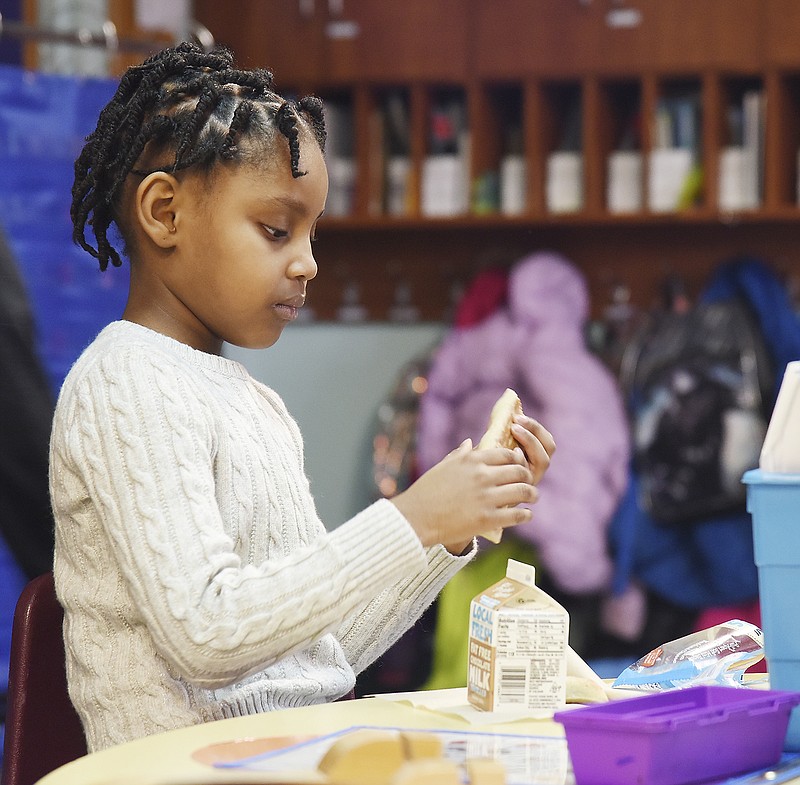 Ma'laysia Johnson breaks apart her bagel into small pieces so she can eat it like a finger food to have with her milk. Students at Moreau Heights are now able to have breakfast in their respective classrooms prior to the start of school.