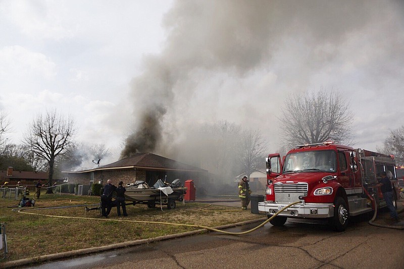 New Boston firefighters work on putting out a fire at a home on Friday, March 8, 2019, in New Boston, Texas.