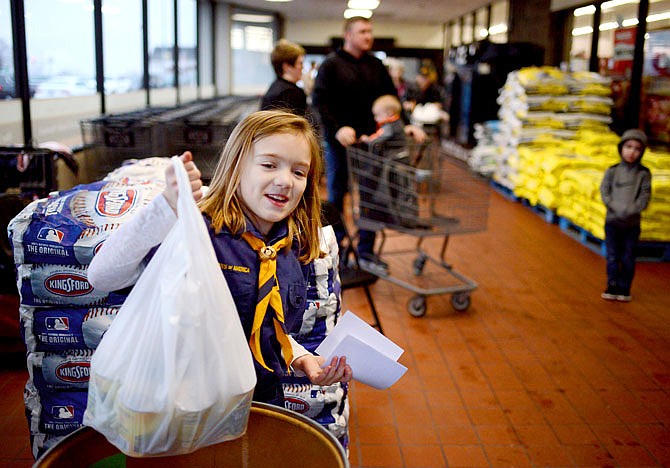 Lorelei Weeks, 8, lifts a bag of canned food into a donation bin Saturday at Schulte's Fresh Foods for the annual Scouting for Food program. Boy Scout and Cub Scout members posted at various locations in Jefferson City and Holt Summit to collect donations for the Samaritan Center. The troops accepted food and cash donations which were then taken directly to the Samaritan Center every few hours. 