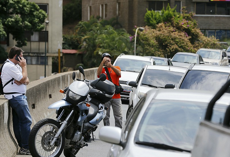 Motorists stop on the road near a working cell phone tower during rolling blackouts in Caracas, Venezuela, Monday, March 11, 2019. Some say the cell phone tower is one of the few in regular operation, transforming the spot into one of the city’s most popular destinations. (AP Photo/Fernando Llano)