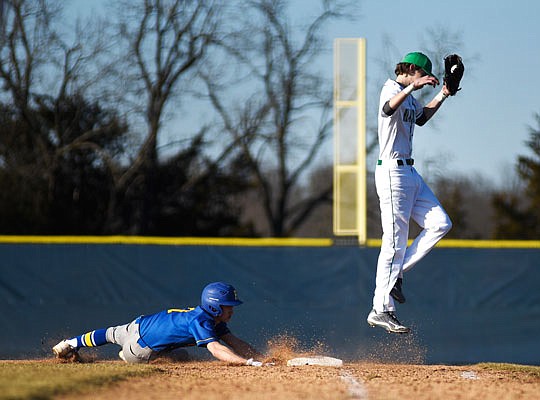 Dawson Peters of Fatima slides back to first base as Jacob Stegemann of Blair Oaks jumps to catch a throw during Monday afternoon's Jamboree at the American Legion Post 5 Sports Complex.