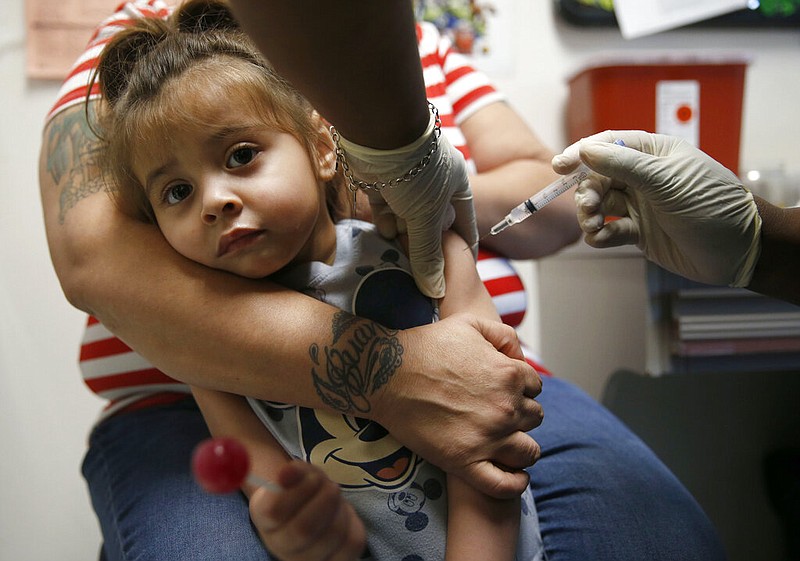 In a Friday, March 8, 2019 photo, Karma Islas, 2, is held by her mother Maria Islas of Dallas as she gets a shot for a vaccine administered by Demetria McRuffin, RN at the Dallas County Health & Human Services immunization clinic in Dallas. North Texas pediatricians say they've found that more and more parents want to be certain their children won't be in a waiting room with children who haven't had their shots, especially in light of recent measles outbreaks around Texas.(Vernon Bryant/The Dallas Morning News via AP)