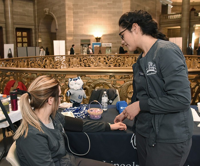 In this Feb. 7, 2018 photo, Angela Arechiga, right, waits while the blood pressure cuff is pumped up to take a reading on Sara Klein during Lincoln University Day at the Missouri Capitol. Students were on hand to represent LU's School of Nursing program. 