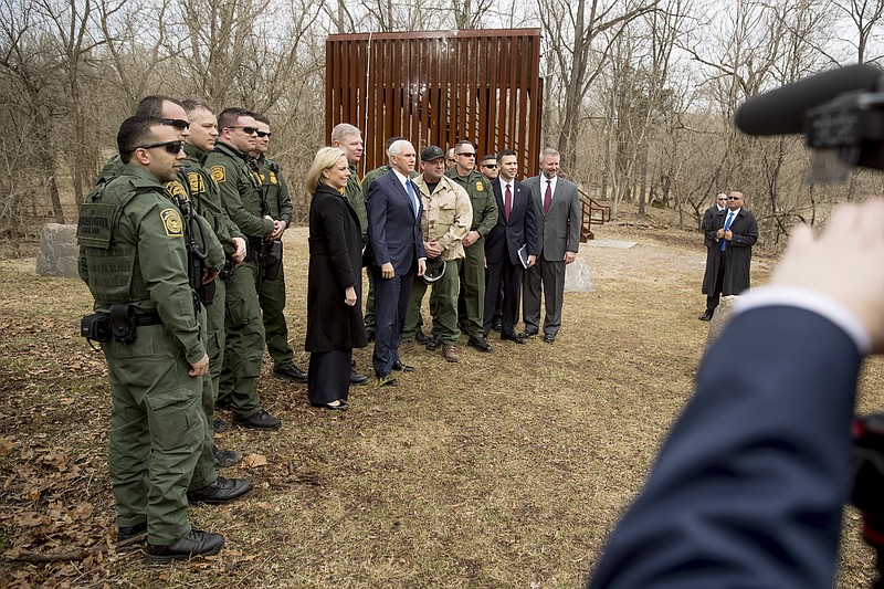 A section of border wall, used for training, is visible behind Vice President Mike Pence, center, and Homeland Security Secretary Kirstjen Nielsen, center left, as they pose for a photograph with Border Patrol agents following a border wall training demonstration at the U.S. Customs and Border Protection Advanced Training Facility in Harpers Ferry, W.Va., Wednesday, March 13, 2019. (AP Photo/Andrew Harnik)